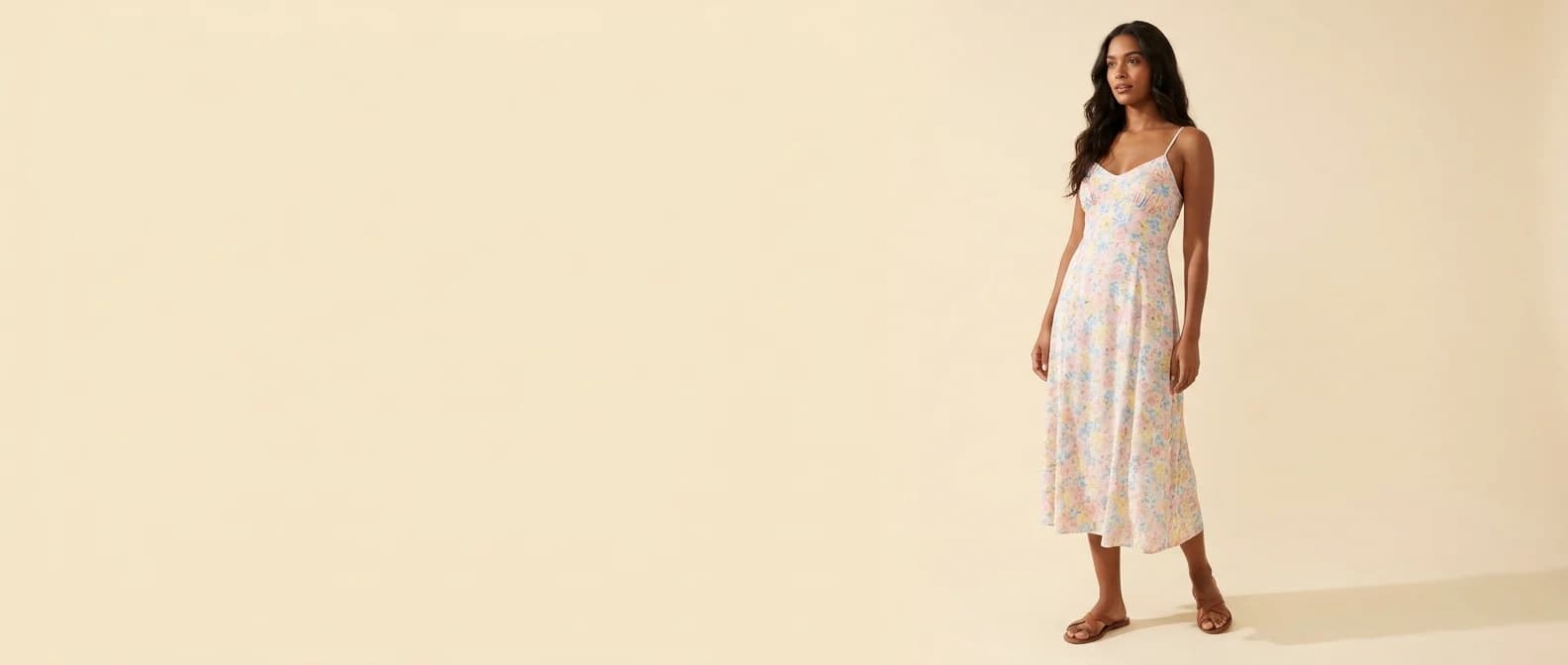 Mujer con vestido midi floral, sobre fondo crema